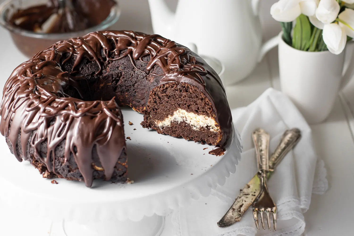 chocolate bundt cake with chocolate ganache on a white cake stand