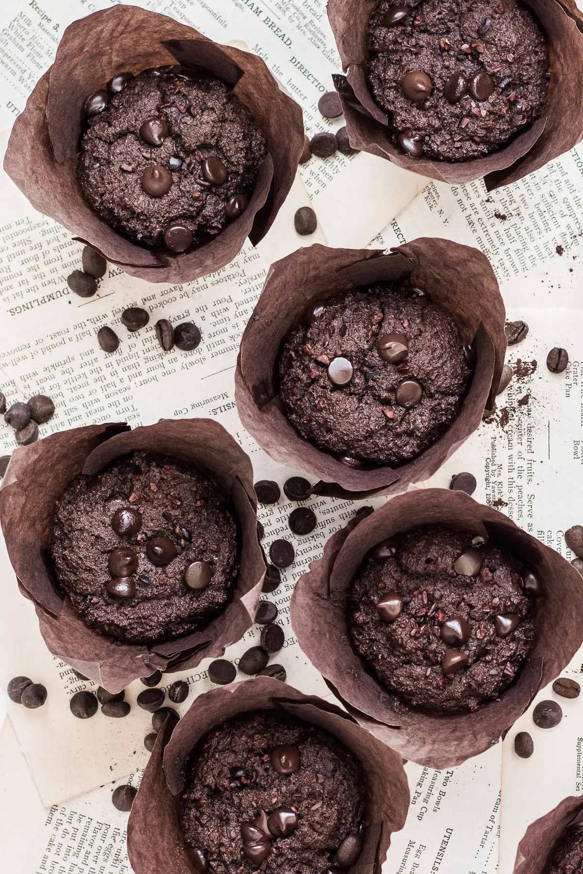 triple chocolate muffins with dark chocolate chips in brown muffin wrappers on a white background