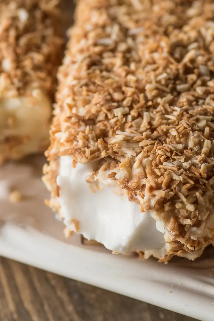 close up shot of the inside of a creamy coconut popsicle surrounded by a toasted coconut shell 