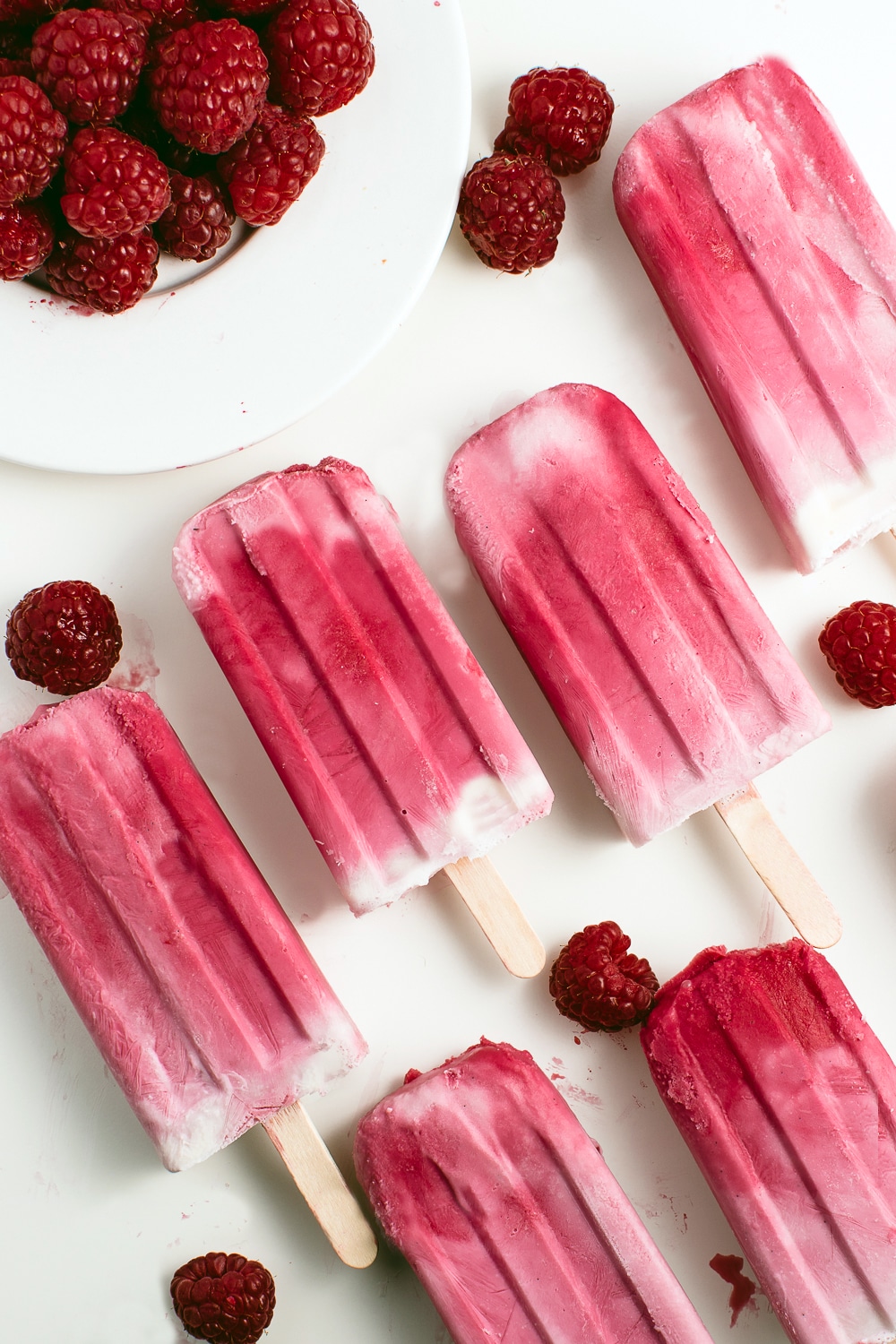 Pink and white raspberry ripple ice cream bars on a white background
