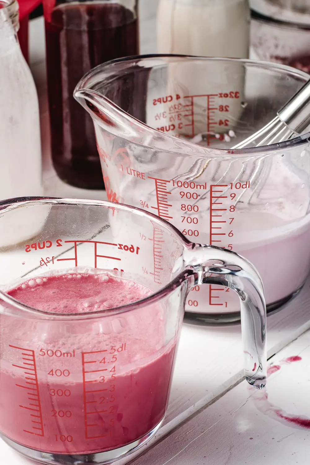 measuring cups filled with cream and raspberry juice