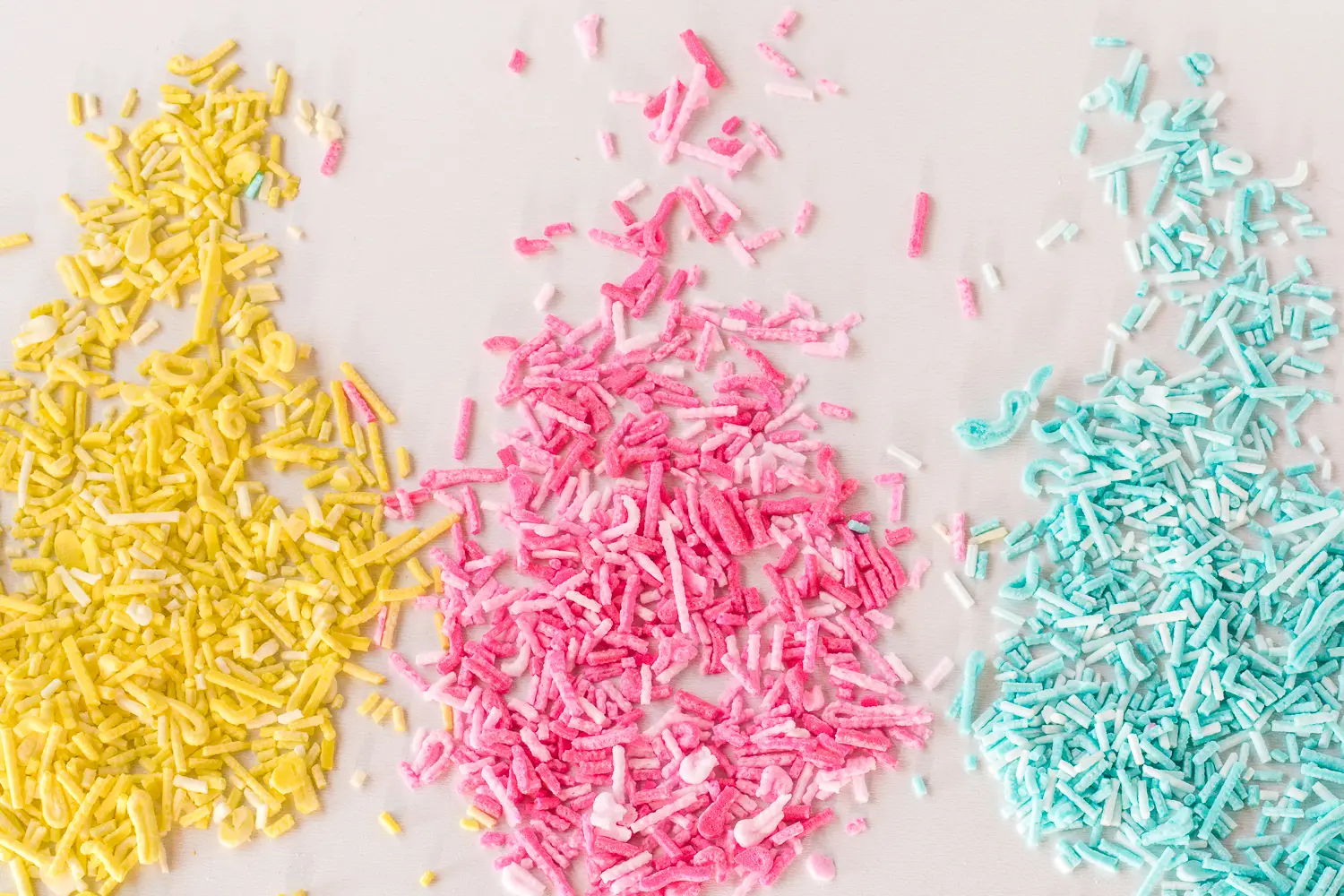 yellow, pink and blue sugar-free sprinkles spread on a white background 