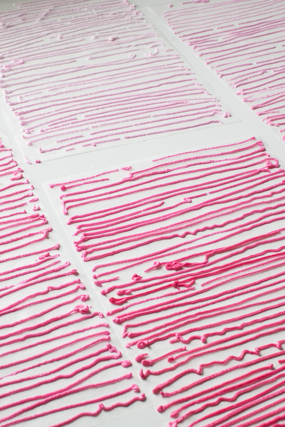 Lines of sugar-free royal icing drying on parchment sheets 