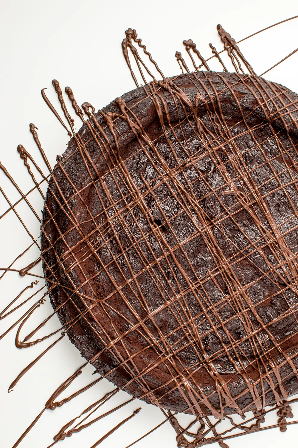 chocolate torte covered in stripes of melted chocolate on a white background