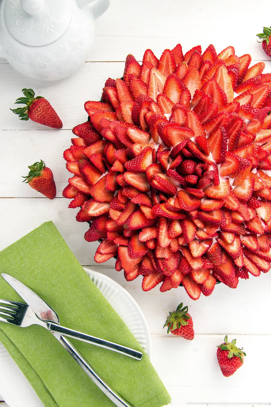 A strawberry cream pie topped with sliced strawberries. The strawberries are arranged in a rose pattern. 