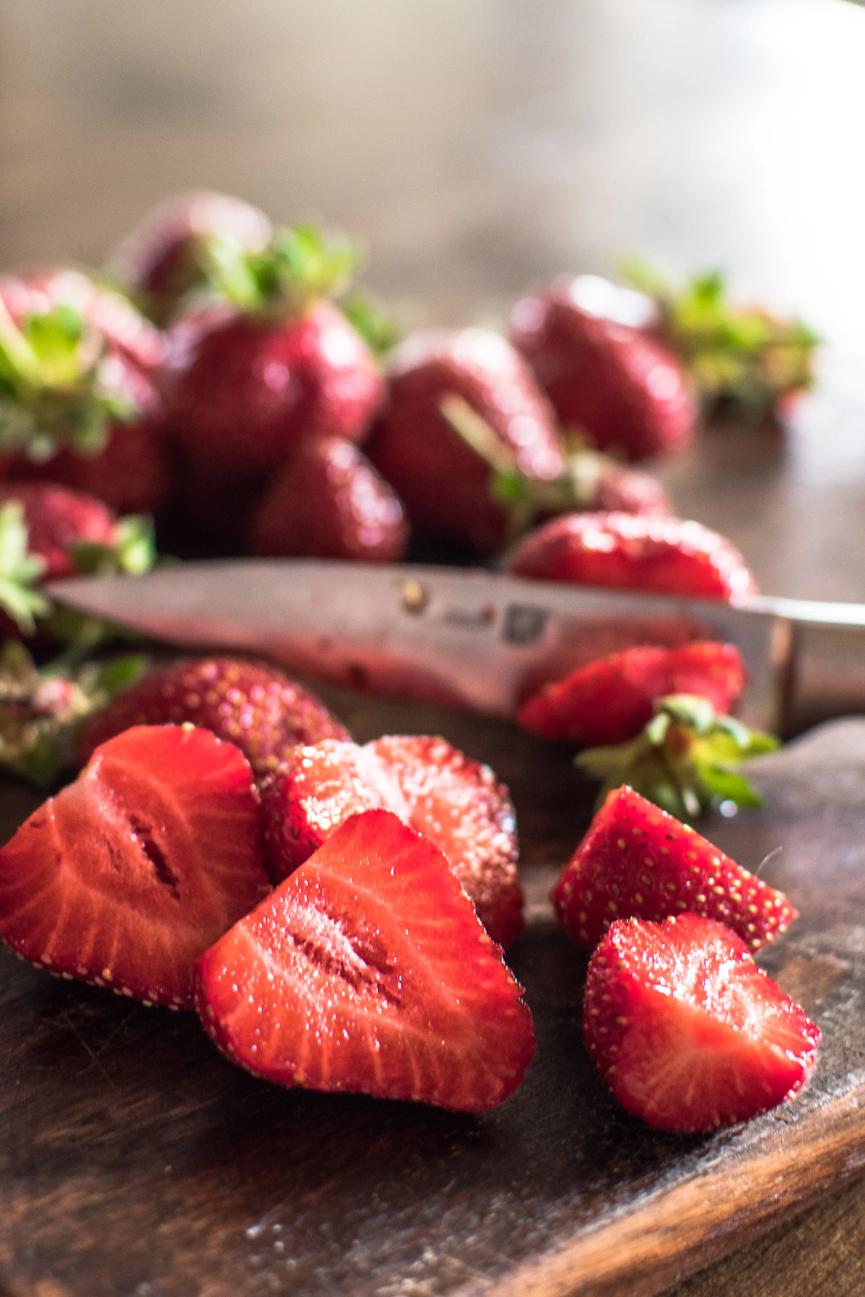 a close up shot of ripe sliced strawberries on a wooden cutting board