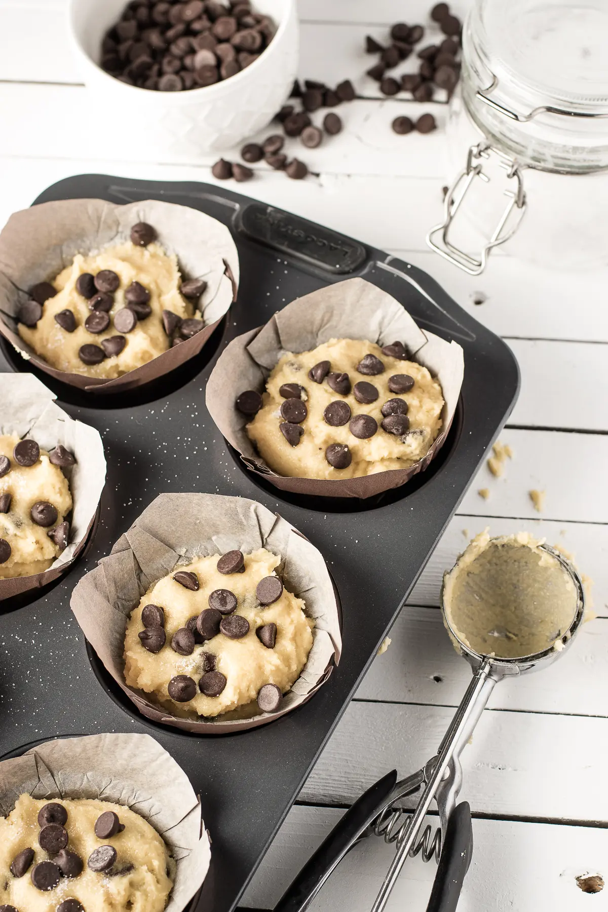 Chocolate chip muffin batter in a muffin tray on a white background