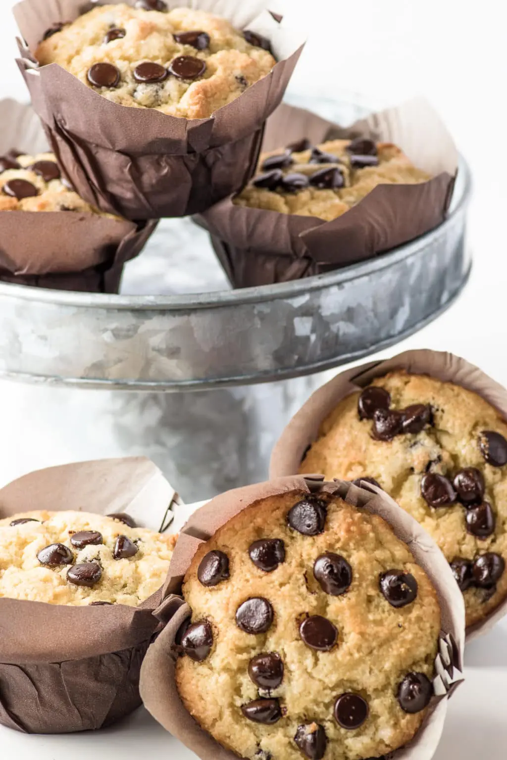 Bakery style chocolate chip muffins stacked on a metal cake stand. 