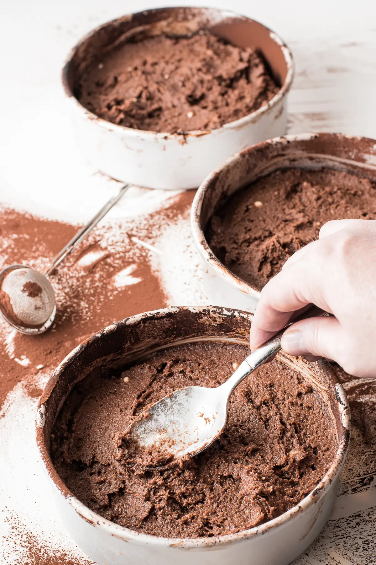 low carb dark chocolate cake batter being spread inside cake pans