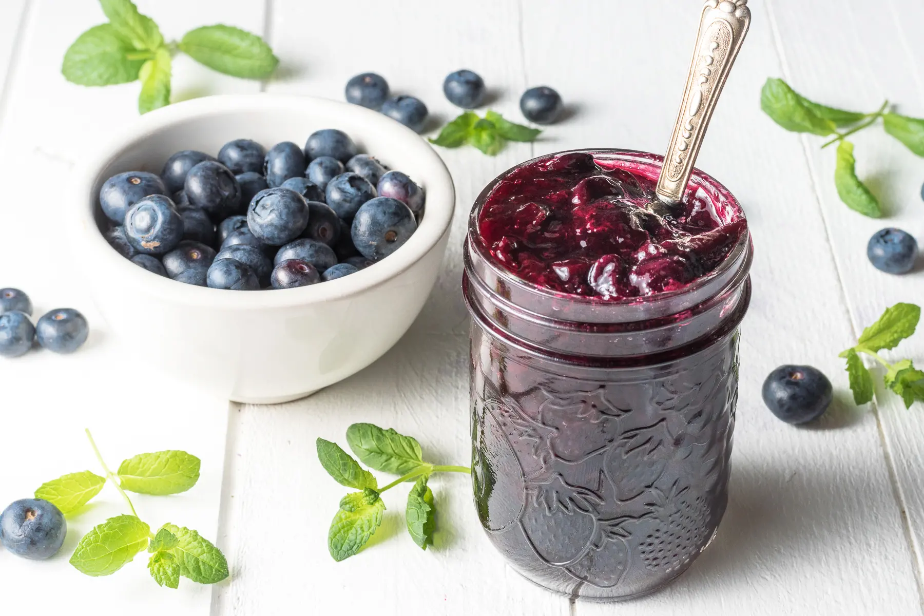 Sugar-free blueberry jam with fresh blueberries, sprigs of mint, on a white wooden board