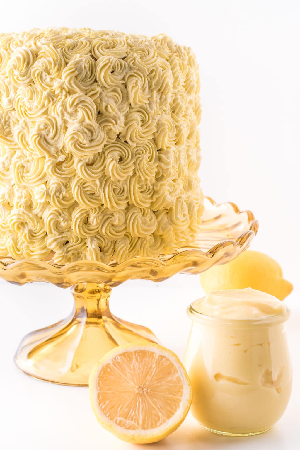 A tall lemon cake with yellow frosting rosettes.
