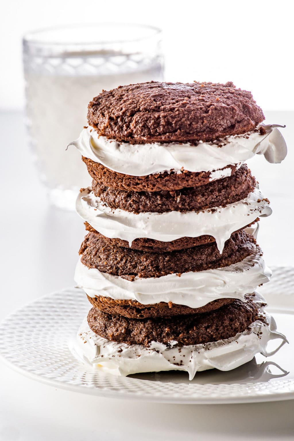 Stacked chocolate whoopie pies stuffed with marshmallow fluff on a white plate