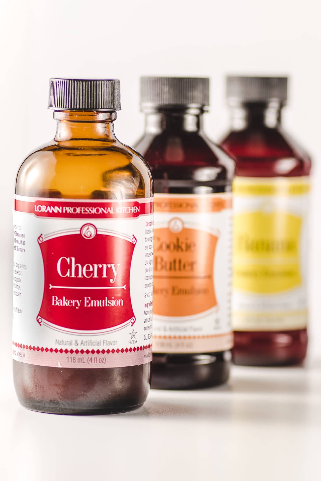 Brown glass bottles of flavored bakery emulssions with brightly colored labels on a white background