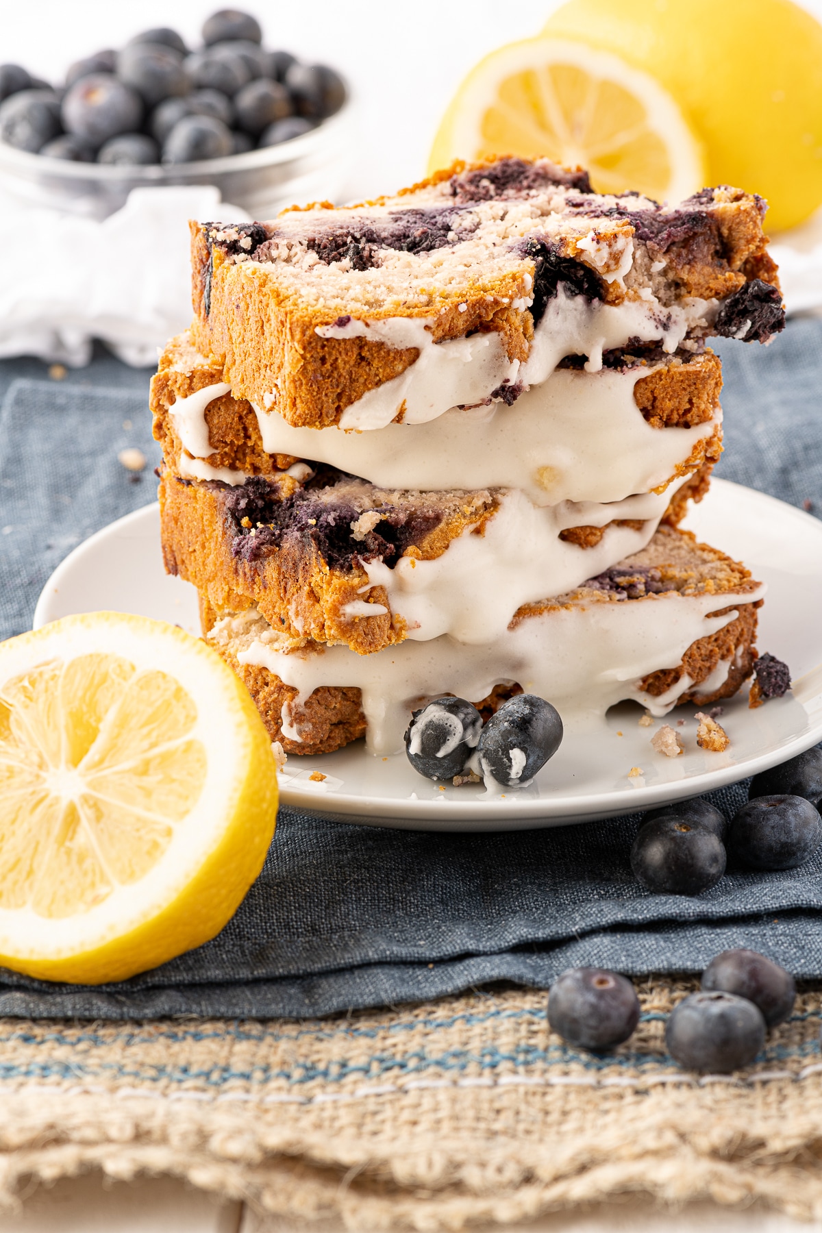 A tall stack of keto blueberry bread slices, with sliced lemon and blueberries in the foreground.