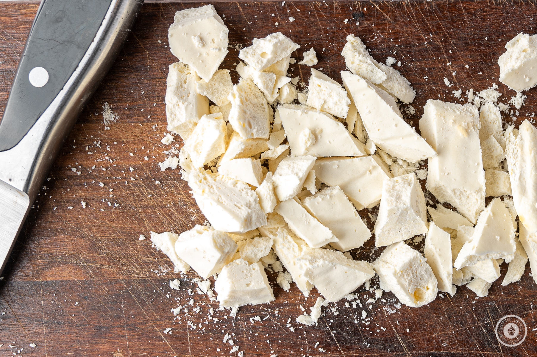 Frozen cheesecake chopped into small chunks on a rustic dark wood cutting board