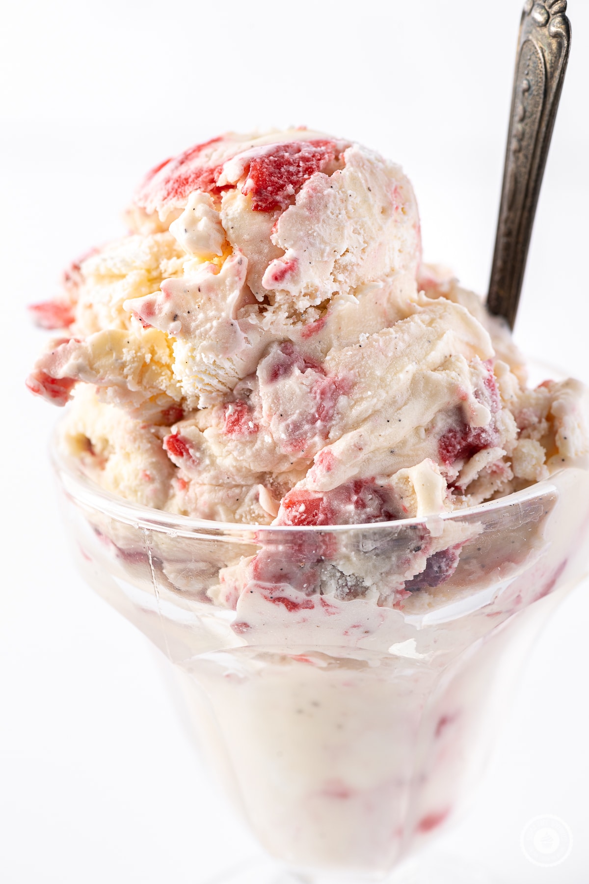 Strawberry cheesecake ice cream scooped into a glass sundae dish with vintage spoon.  