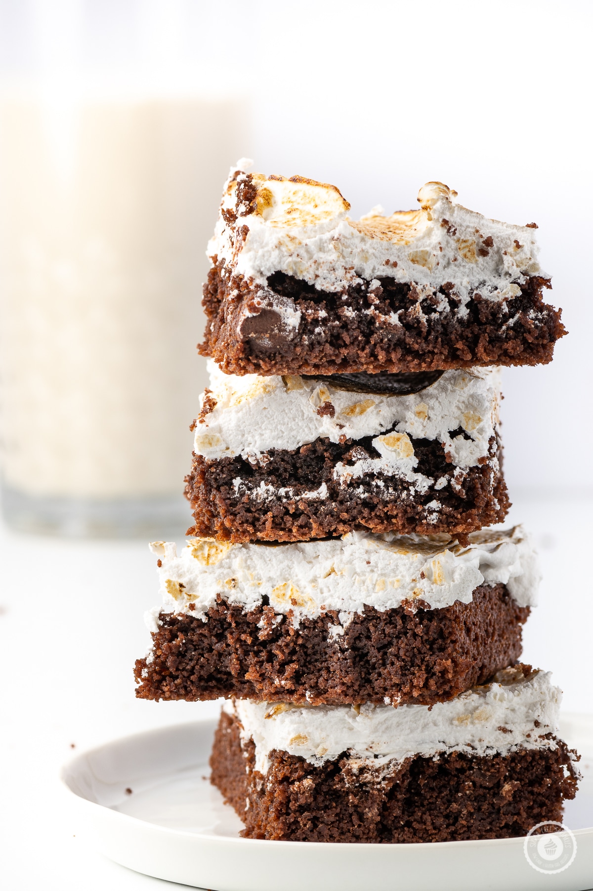 Low carb chocolate brownies with toasted marshmallow topping stacked  on a small white plate against a bright white background 