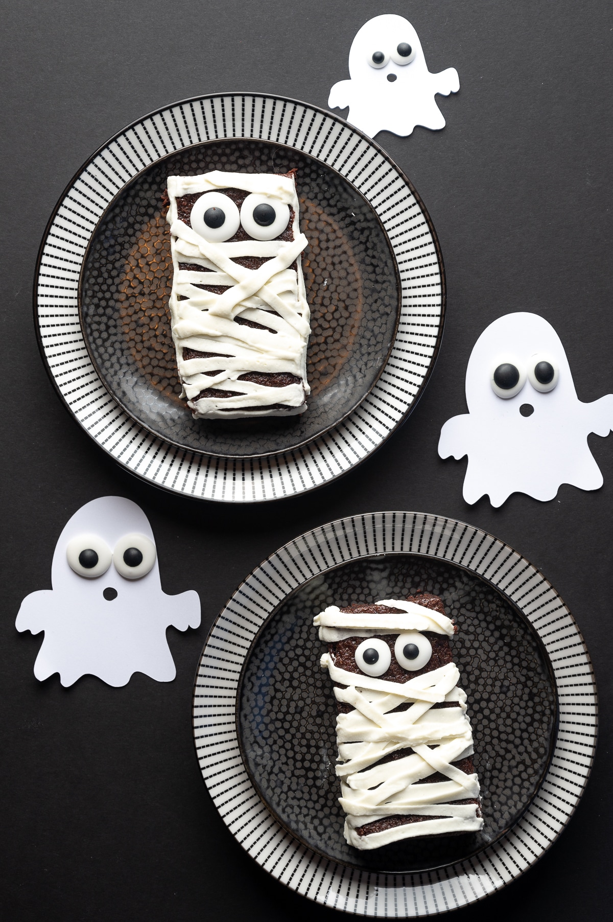 Sugar free brownie with googly eyes and frosting applied in strips to look like bandages on a black background