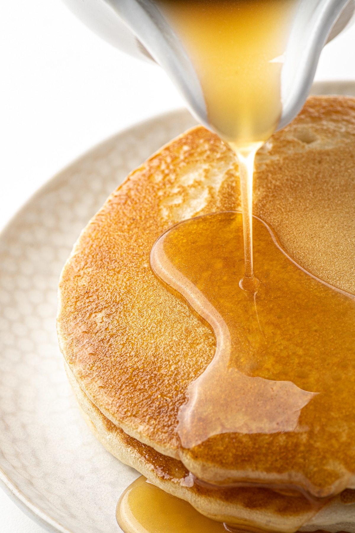 Pancakes being covered in syrup made from this keto maple syrup recipe.