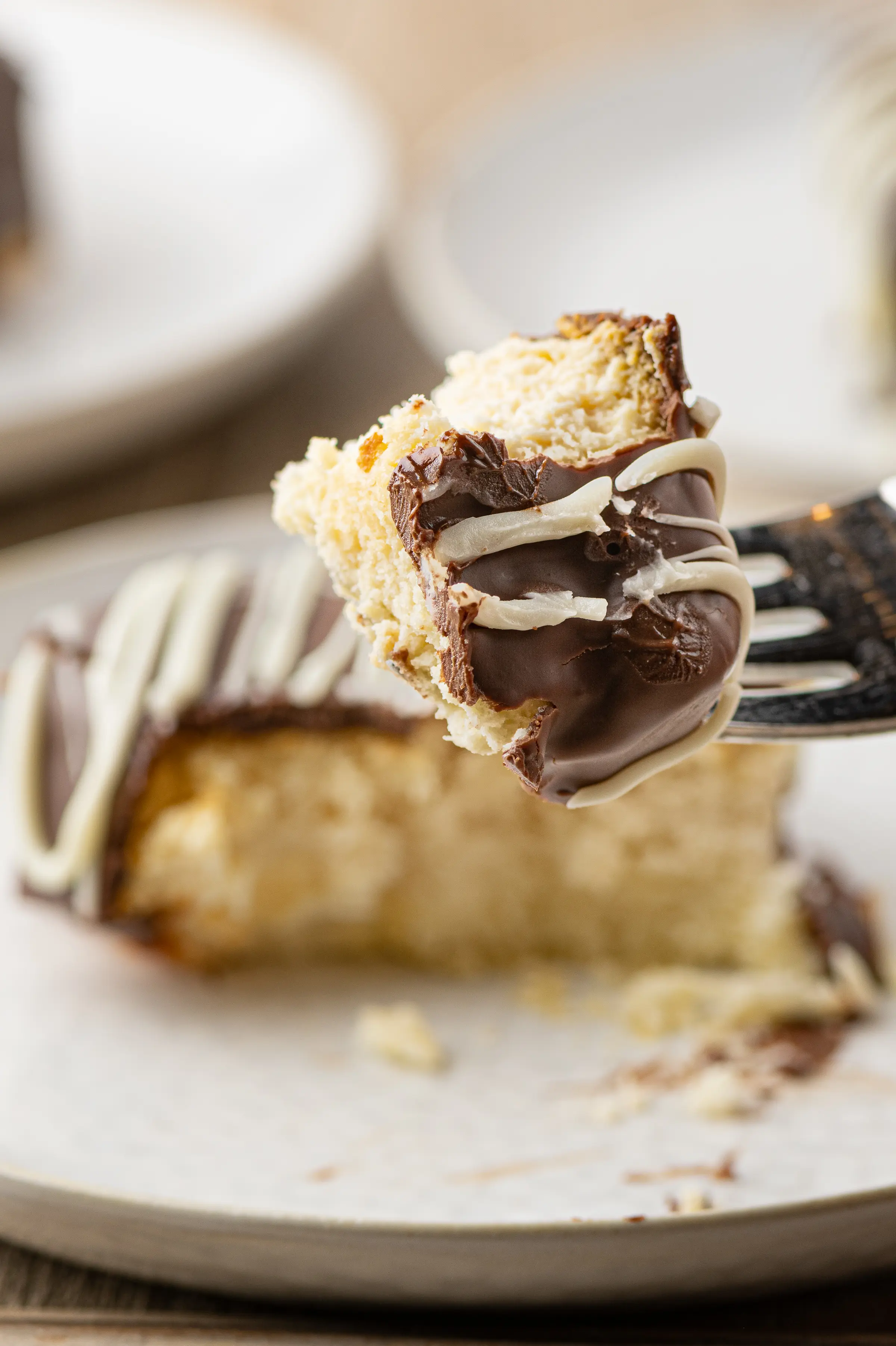 A fork with a piece of keto cheesecake bite coated in chocolate. 