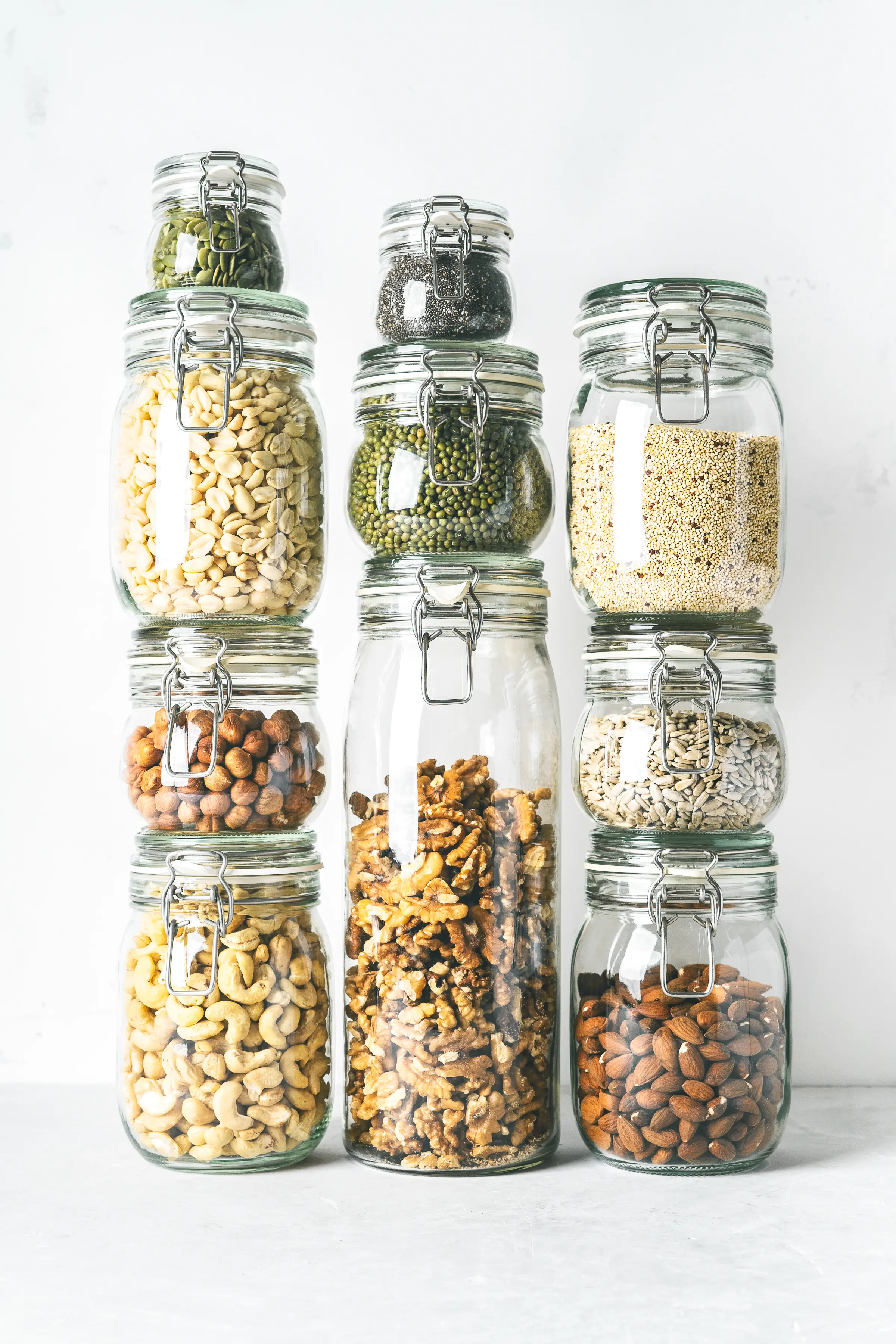 Glass jars stacked filled with low carb panty essential nuts and seeds