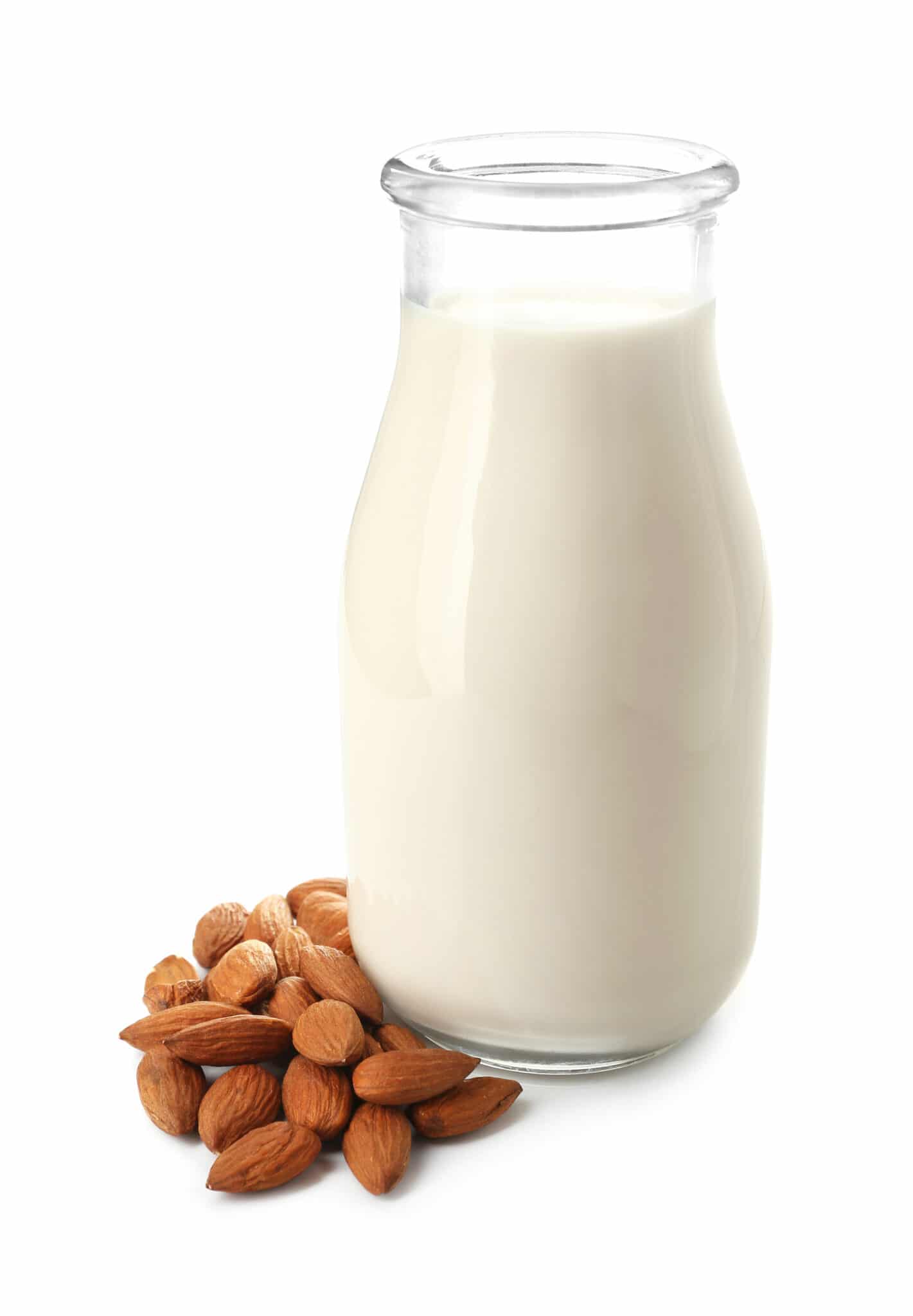 A tall glass bottle of almond milk, with a small pile of almonds beside it.
