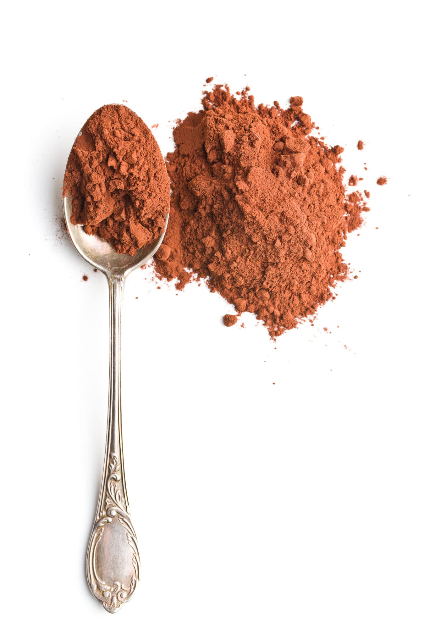 A silver tablespoon filled with cocoa powder isolated on a bright white background.