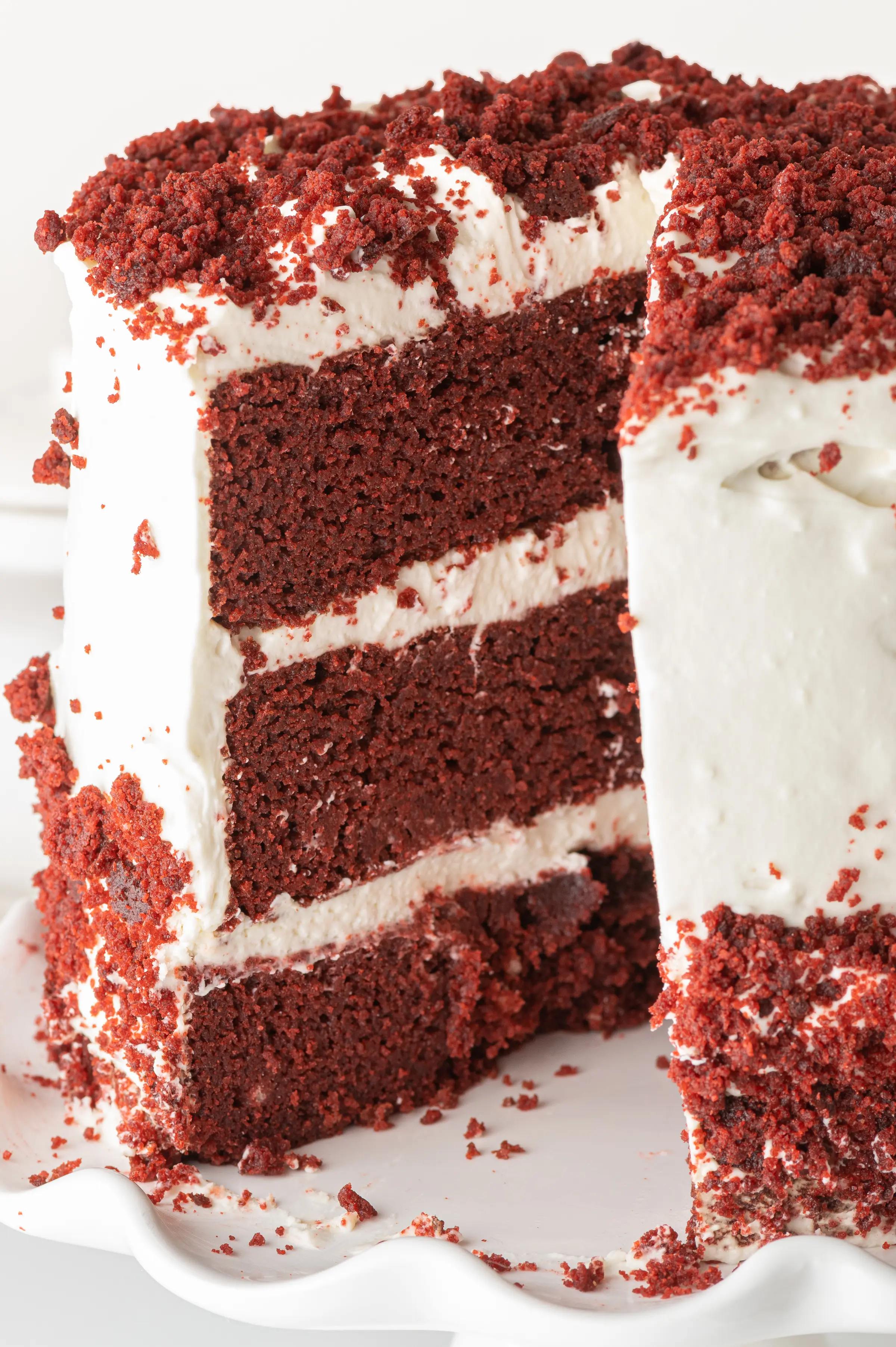 Low carb red velvet cake with white cream cheese frosting.  A slice is a removed and you can see the maroon layers contrasted against the bright white frosting. 