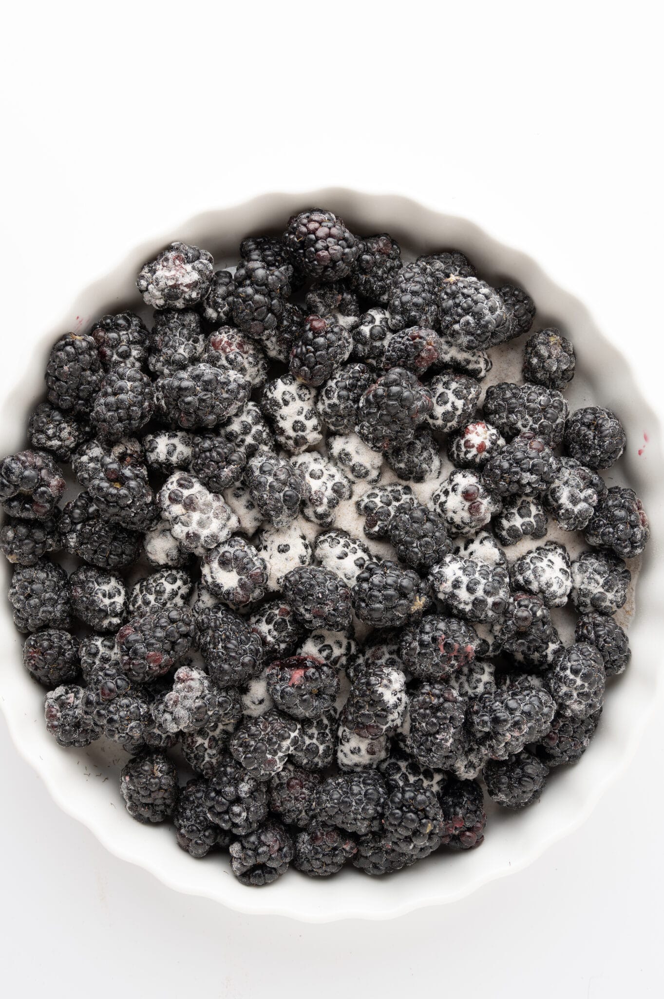 Sweetener coated blackberries in a white tart pan. 