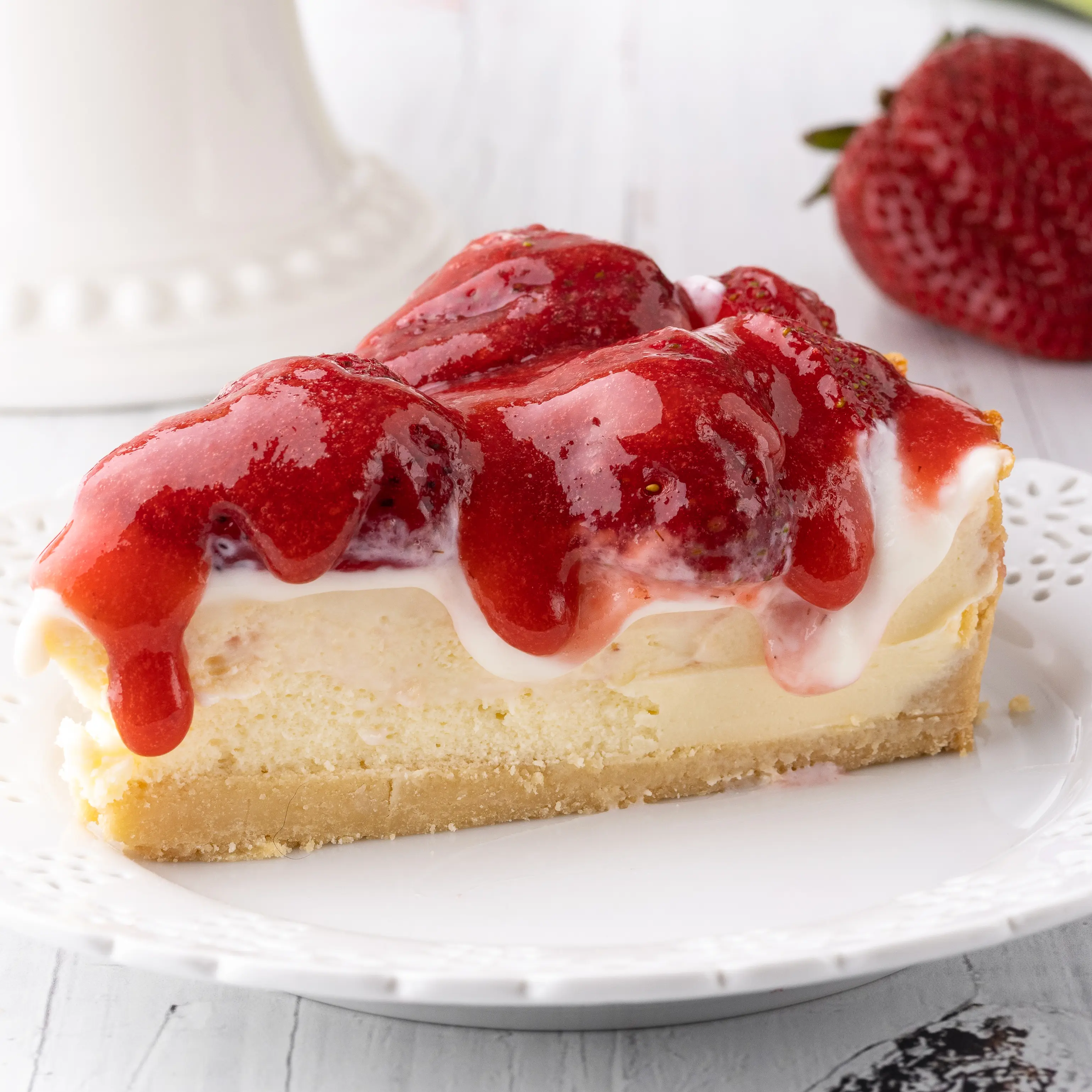 A slice of strawberry cheesecake dripping with sour cream and strawberry sauce topping. 