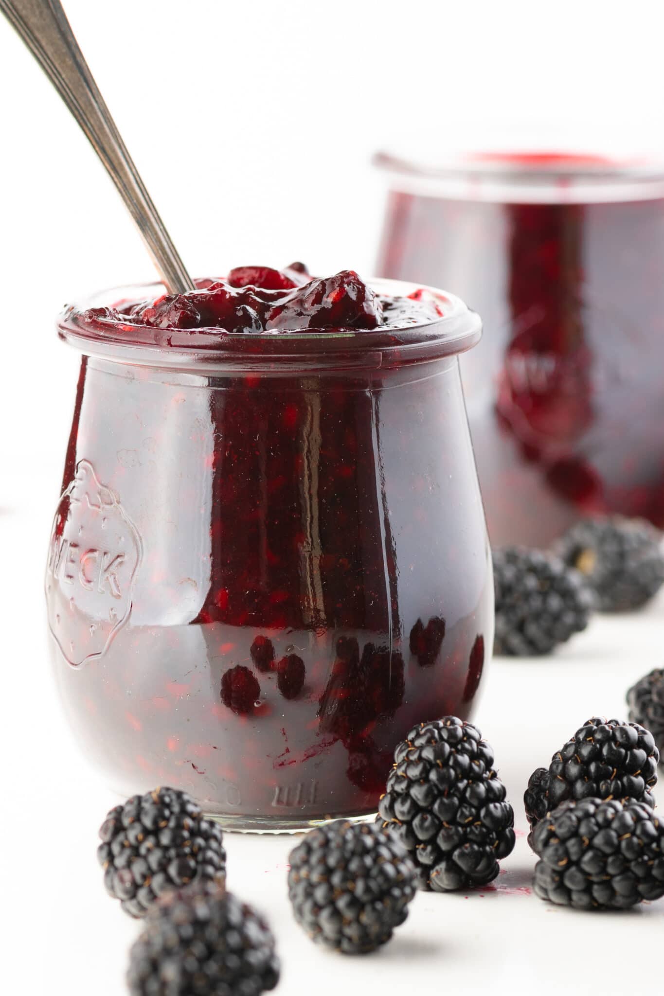 A small jar of sugar-free blackberry jam with a spoon dipped into it.