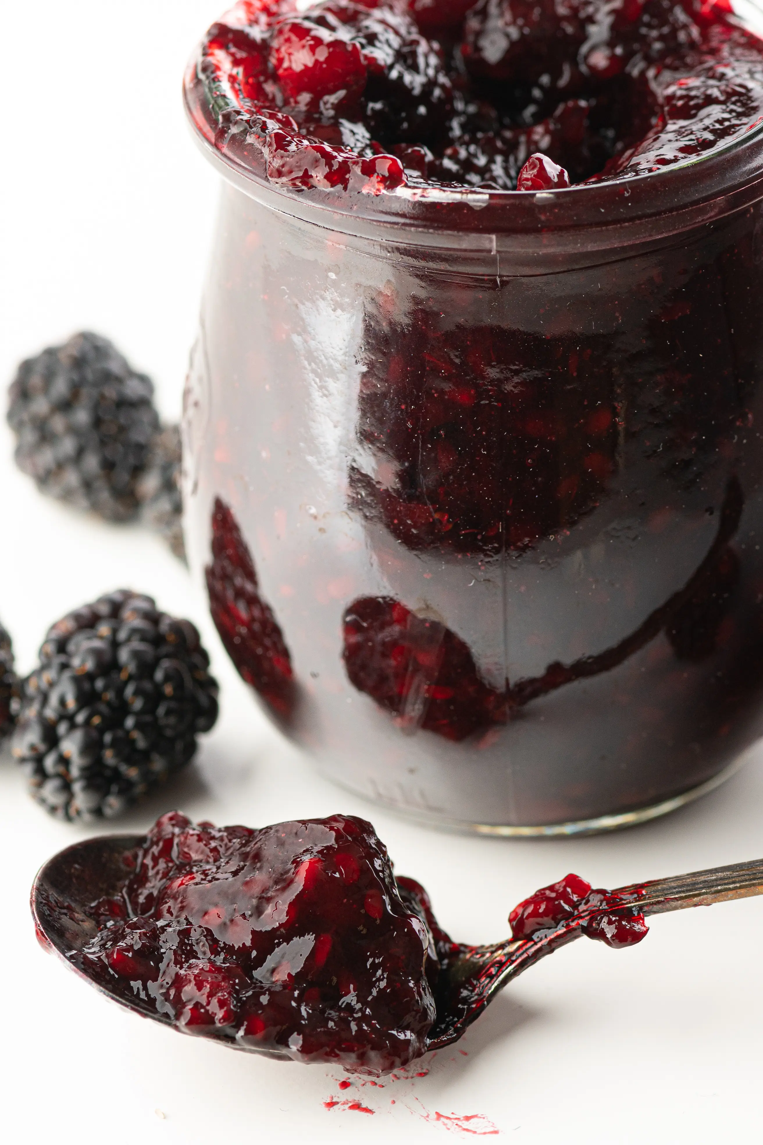 A jar of sugar-free blackberry jam, with a spoonful sitting beside them.