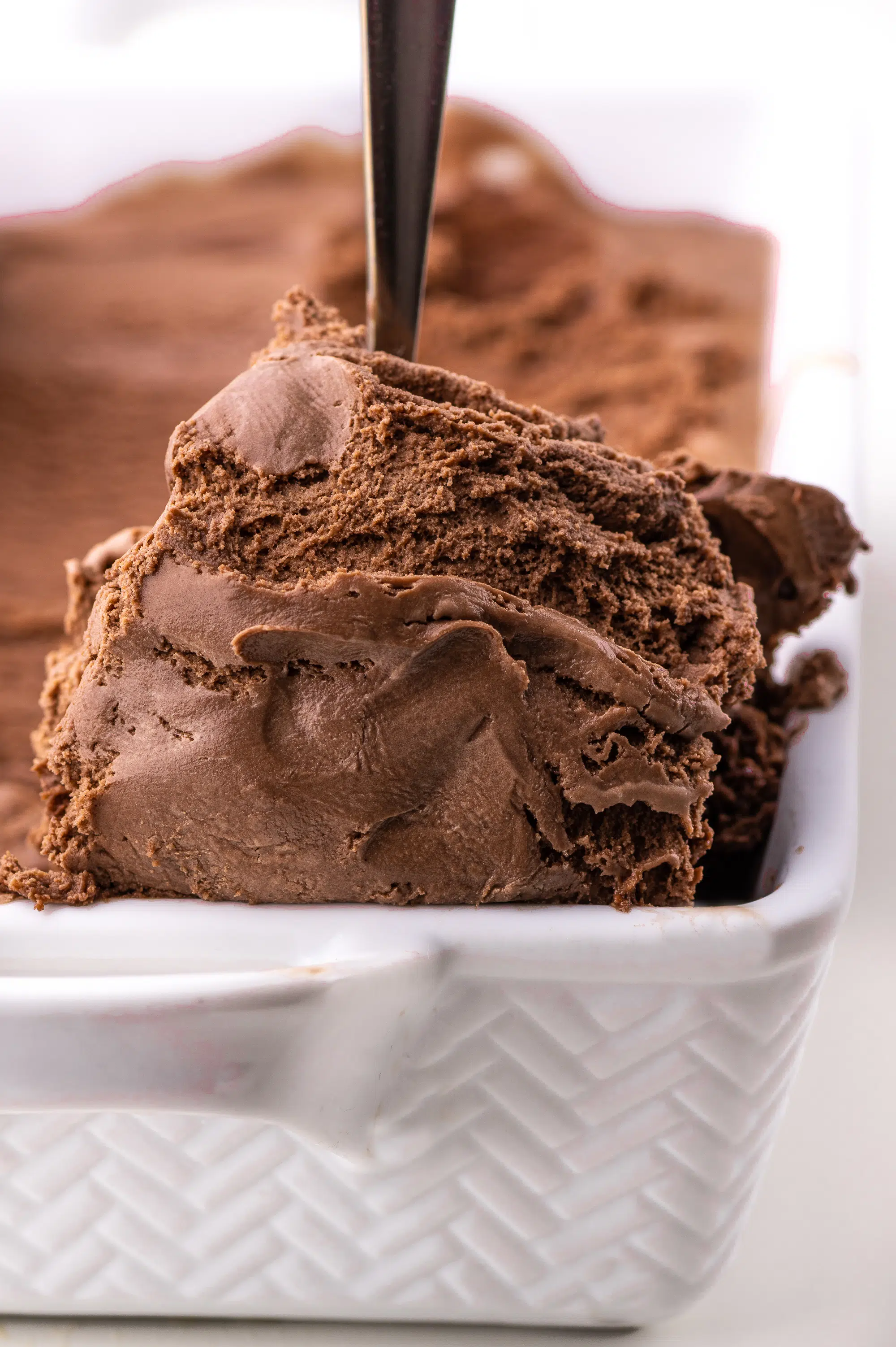 Keto chocolate ice cream being scooped from a dish.