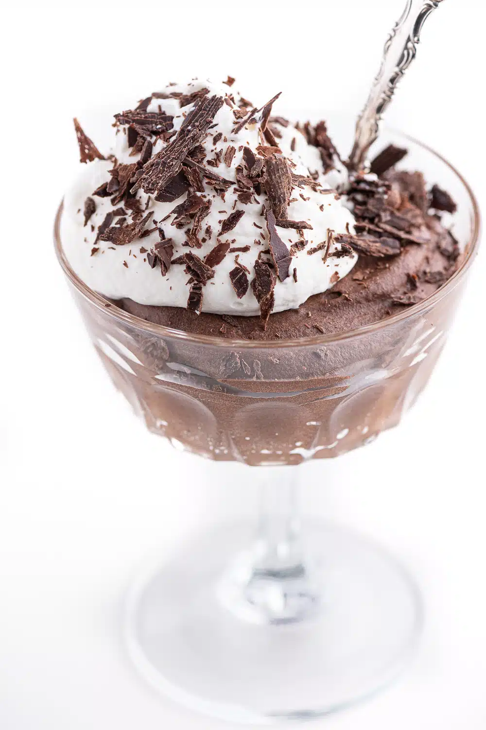 Keto chocolate mousse in a crystal stemmed serving dish with a dollop of fresh whip cream and dark chocolate shavings. 