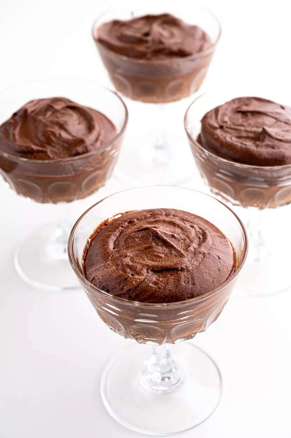 4 dishes of chocolate mousse against a bright white background. 